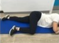 A person lying on their side on an exercise mat with their bottom leg out straight and their top leg bent at a 90 degree angle.